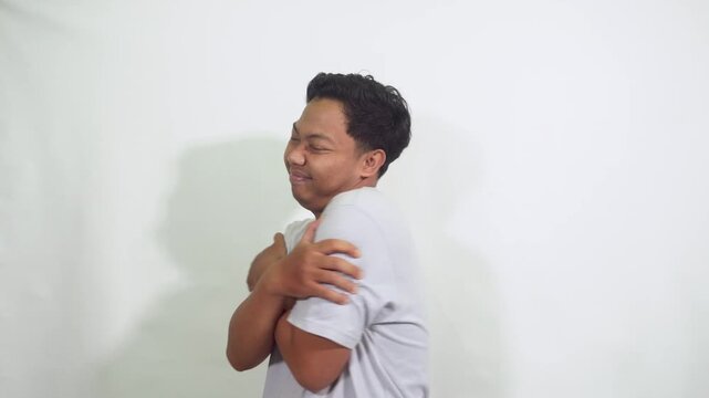 man hug himself with smiling face in isolated studio wearing plain tshirt