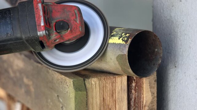 Selective focus on an electric grinder machine cleaning metal surface before welding