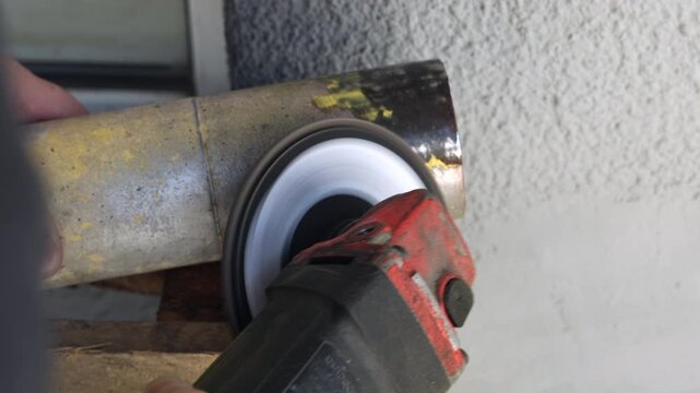 Macro shot of grinding power tool removing yellow paint and rust from steel tube