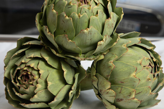 Trois chardons verts sur une table, avec un fond flou de voiture