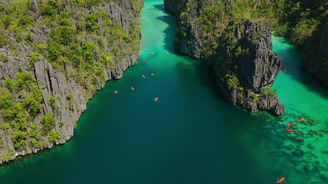 Aerial Backwards Tracking Shot Over Deep Channel at Big Lagoon in El Nido, Philippines. Drone Pull Away View over Dark Blue Water Framed by Towering Limestone Karst Cliffs.