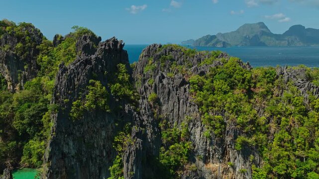 Aerial Forward Reveal Shot Over Limestone Cliffs at Small Lagoon in El Nido, Philippines. Drone View Flying Over Karst Mountain Peaks to Unveil Hidden Turquoise Water.