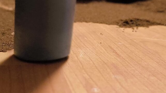 Cleaning ground coffee powder off a wooden surface with a vacuum cleaner nozzle. 