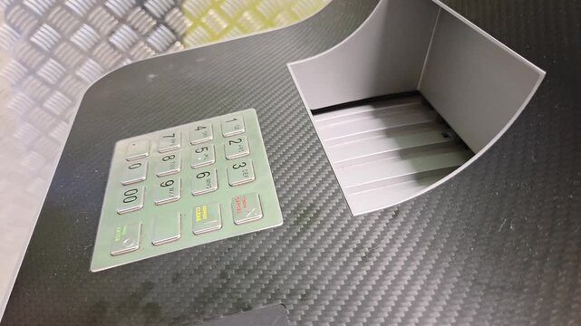 Person entering PIN on ATM keypad using contactless card