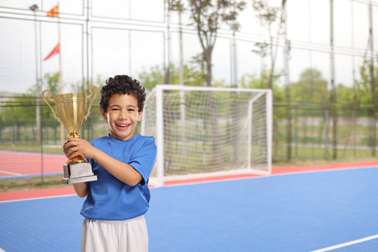 Kid in sports jersey holding a gold tropy cup
