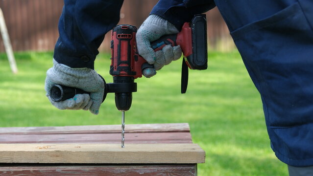 Builder worker using cordless hammer drill. Man with pneumatic perforator equipment making hole at construction. Installation process. Gloved hand grips the tool, precision and safety while working.