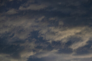 Obraz premium Dark moody cloudscape with layered grey and golden-tinged clouds