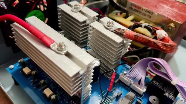 Side view of an open green electronic device chassis showcasing complex internal wiring, circuit boards, and heatsinks.