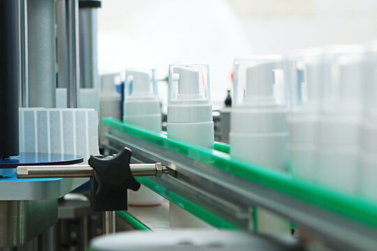 White plastic bottles without labels on conveyor belt. Conveyor belt for cosmetics production. Cosmetics production. Labeling machine