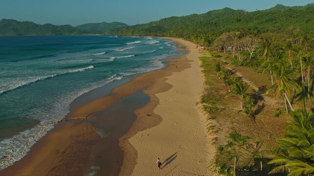 Aerial Rocket Shot Over Duli Beach in El Nido, Philippines. Cinematic Drone Vertical Ascent and Reveal View of Golden Sand Shoreline, Rolling Surf, and Beach Crowd.