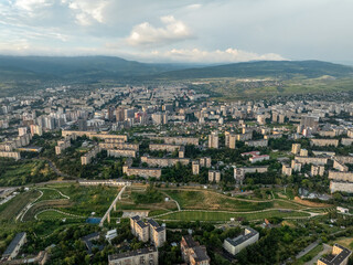 Obraz premium High-angle aerial drone panorama of large residential areas in Tbilisi, Georgia. The shot highlights dense Soviet-era concrete block apartments mixed with modern developments