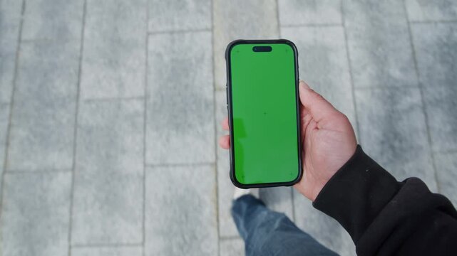 A man walks along a bustling street, capturing the vibrant world around him. His smartphone displays a blank screen, inviting imagination and creativity in this lively urban scene