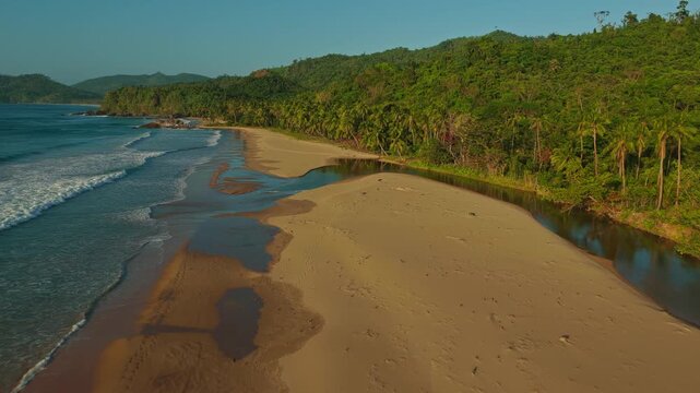 Aerial Forward Tracking Shot Along the Far End of Duli Beach in El Nido, Philippines. Drone View of Sweeping Golden Sand Shoreline, River Estuary, Rolling Surf, and Tropical Jungle.