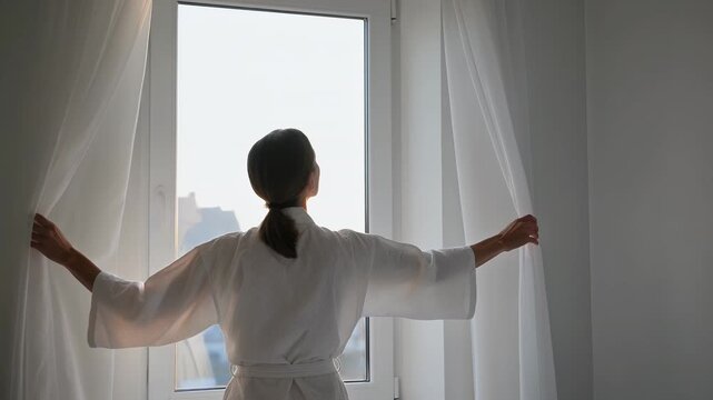 Woman, opening curtains and morning routine in bedroom with window, light and wellness for start of day. Female, bathrobe and vision with new beginning, sunshine and house for fresh wake up.