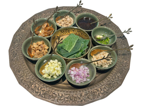 Miang Kham is a traditional Thai snack consisting of various ingredients wrapped in a cha-plu leaf wild betel leaf. A meticulously arranged platter showcases an array of finely chopped ingredients.