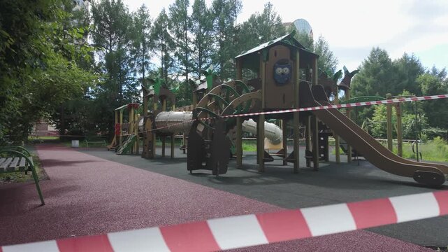 Closed playground with red and white barrier tape restriction in park
