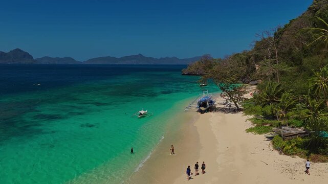 Aerial Forward Tracking Shot Along Seven Commandos Beach Shoreline in El Nido, Philippines. Drone View of Pristine White Sand, Turquoise Ocean, and Dense Tropical Jungle.