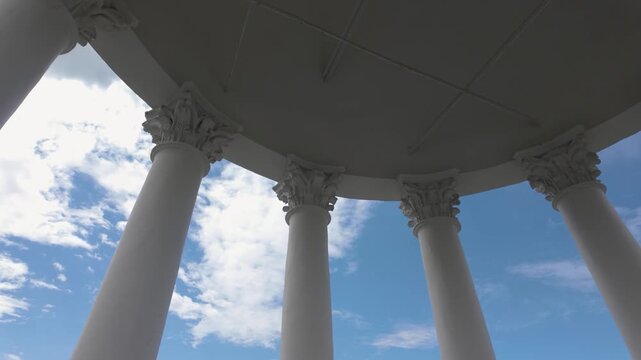 Perspective view between classical white columns against blue sky