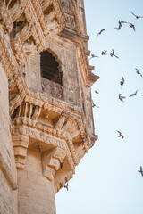 Obraz premium Historic sandstone tower with birds against blue sky 