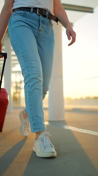 Woman confidently pulling a suitcase in an airport terminal. Slow motion.