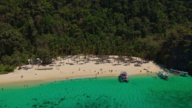 Aerial Orbit of Seven Commandos Beach with Gimbal Movement in El Nido, Philippines. Drone Flying Right to Left Over Turquoise Ocean, White Sand Shoreline, and Dense Jungle.