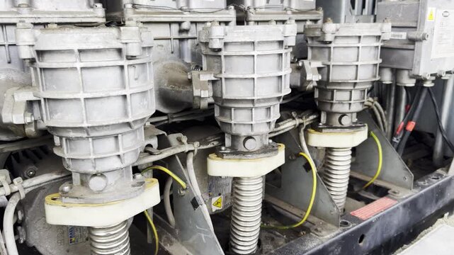 Industrial machine shows spring mounted drive units in modern factory. Metal housings hold aligned parts supporting heavy mechanical motion