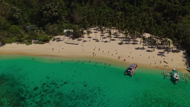 Aerial Vertical Ascent Over Ocean at Seven Commandos Beach in El Nido, Philippines. Cinematic Drone Pedestal Up Looking Towards Tropical White Sand Shoreline and Jungle.