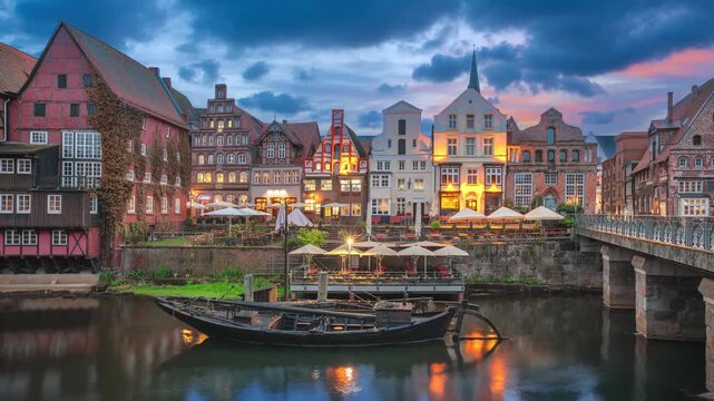 Luneburg, Germany - view of old buildings on еру embankment of Ilmenau river at dusk  (static image with animated sky and water) 