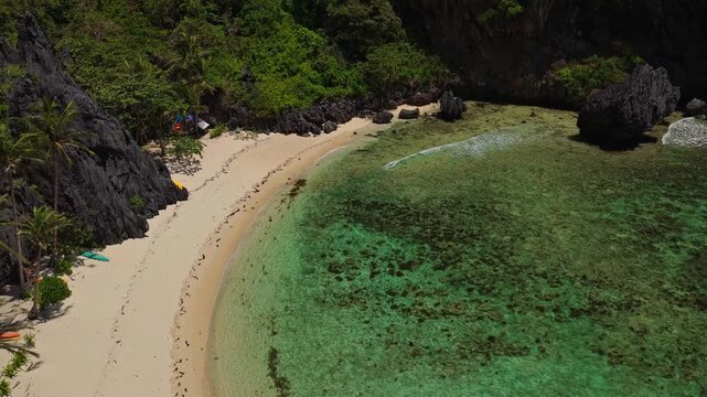 Aerial Orbit of Isolated Beach Near Secret Lagoon in El Nido, Philippines. Drone Flying Left to Right Over Turquoise Ocean, Coral Reef, and Secluded White Sand Shoreline.
