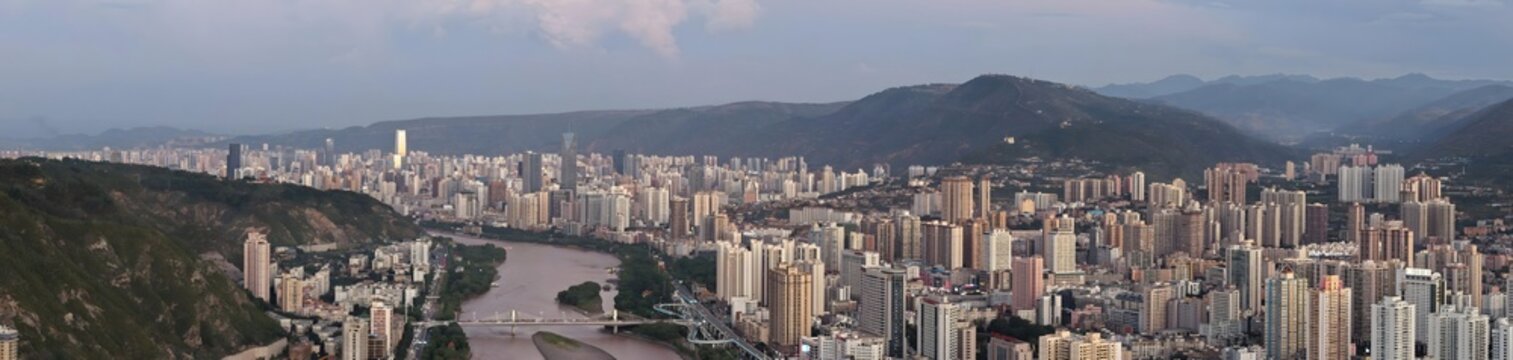 Panoramic skyline of Lanzhou, Gansu, China along the Yellow River at dusk