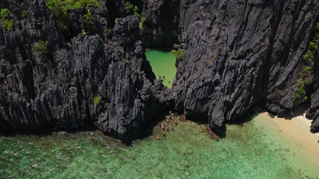 Aerial Forward Shot and Top Down Tilt Over Secret Lagoon in El Nido, Philippines. Cinematic Drone Approach of Hidden Turquoise Water and Dramatic Limestone Cliffs.