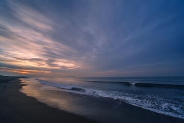 Fototapeta premium Dramatic sunset over a quiet sandy beach and calm sea