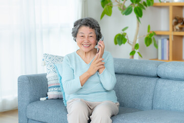 Naklejka premium リビングで電話するシニア女性