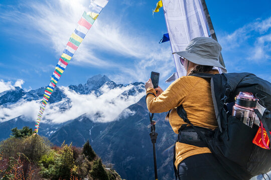 Mujer senderista tomando una foto de las banderitas con rezos budistas, en su camino al Everest Base Camp, en Nepal	