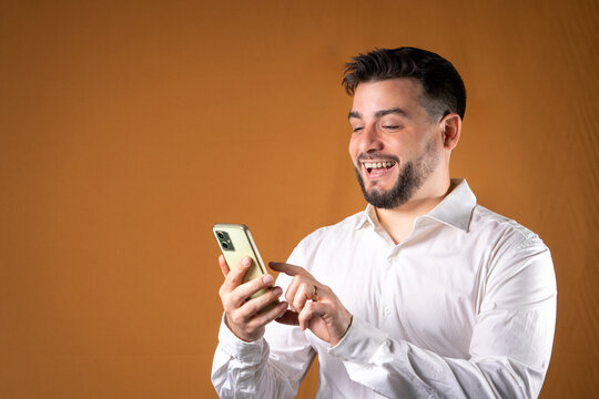 Hombre sonriente y exitoso usando su tel&eacute;fono tocando su pantalla. Concepto de comunicaciones y atenci&oacute;n.