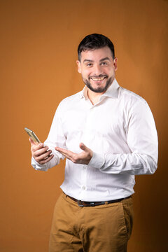 Hombre sonriente y exitoso mostrando su tel&eacute;fono. Ideas para comunicaciones y atenci&oacute;n