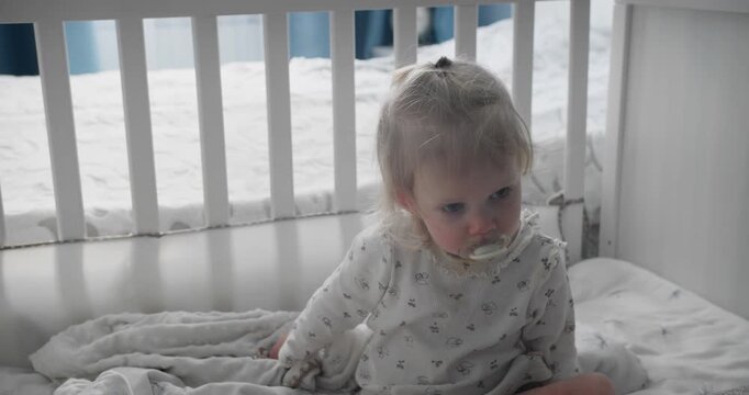 Young child lying awake in protected crib space. Home childcare and safe sleep arrangement
