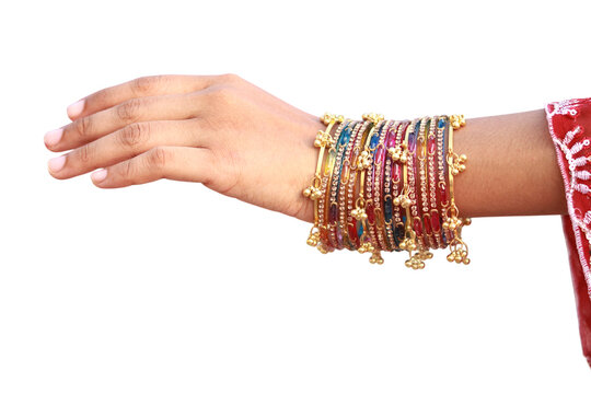 Elegant woman wearing colorful traditional indian bangles with small golden bells on her wrist captured in a close up shot against a plain white studio background.