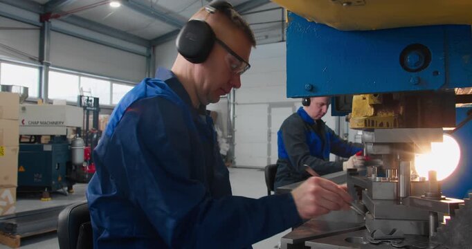 Factory workers operating industrial machinery during routine manufacturing operations in a metal fabrication workshop