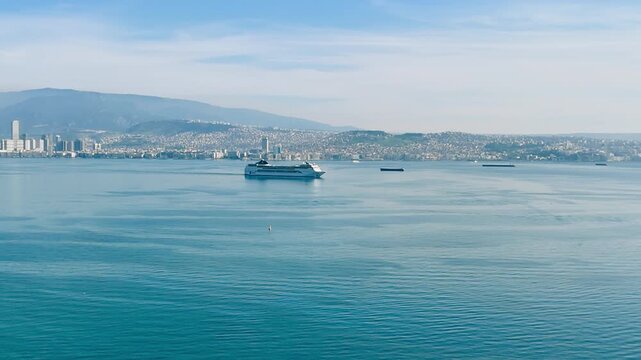 Cruise liner sailing in sea bay along city coastline. Aerial view for travel industry, cruise demand and tourism business