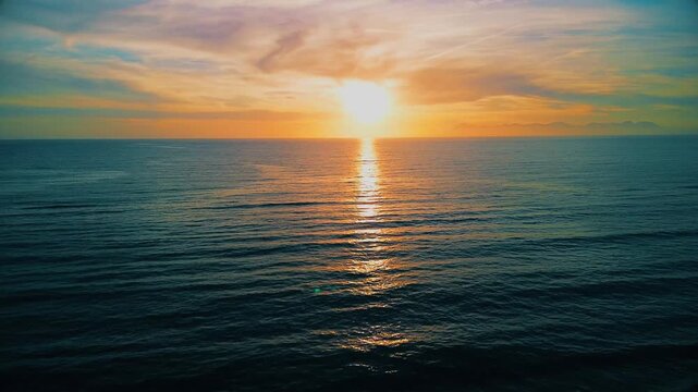 A breathtaking panoramic view of a dramatic golden sunset over the Mediterranean Sea in Agropoli, Cilento coast. The sky is filled with vibrant hues of orange, pink, yellow, and blue clouds, while the
