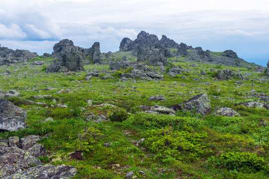 Summer mountain landscape with green meadow and rocks on a background of blue sky