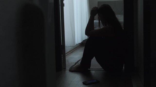 Heartbroken woman sitting alone after breakup with phone nearby, loneliness, emotional pain and relationship loss in authentic home lifestyle setting