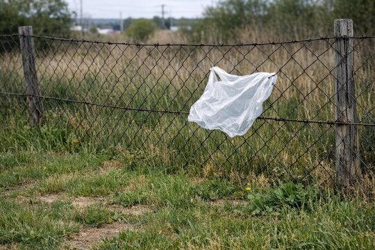 A plastic bag hangs from a farm fence in a rural setting