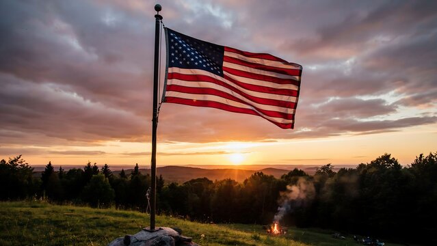 American flag waving on a pole at sunset with a burning fire