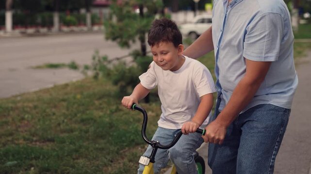 man teach child kid son boy ride bike park, happy family, happy smile face, wind children's hair, concept father child play entertainment keep balance training, adrenaline horse riding, boy son happy