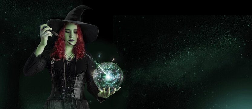 Witch with a magic wand casts a spell with magic Crystal ball for predictions fortune-telling. Young woman, magician girl with red hair, dressed in Halloween clothes and conical hat.