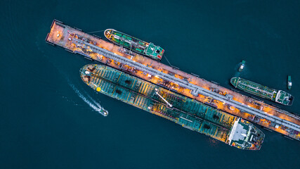 Aerial top view of oil tanker ship at the port, Aerial view oil terminal is industrial facility for storage of oil and petrochemical products ready for transport to further storage facilities. © William
