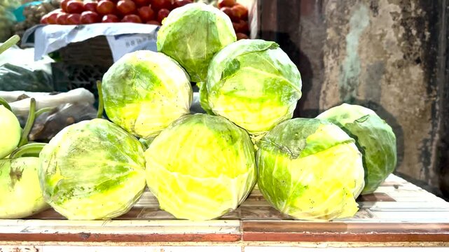 Fresh Cabbage Display: A vibrant display of fresh, green cabbages arranged in a rustic market stall, hinting at a healthy and natural food source.