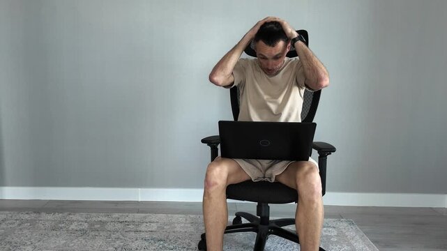Stressed freelancer working remotely on a laptop getting angry and frustrated. Exhausted man overwhelmed by computer problems or bad news
